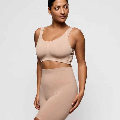 Primadonna Nudda shapewear high briefs with legs in caffe latte on a model standing confidently in a nude outfit.
