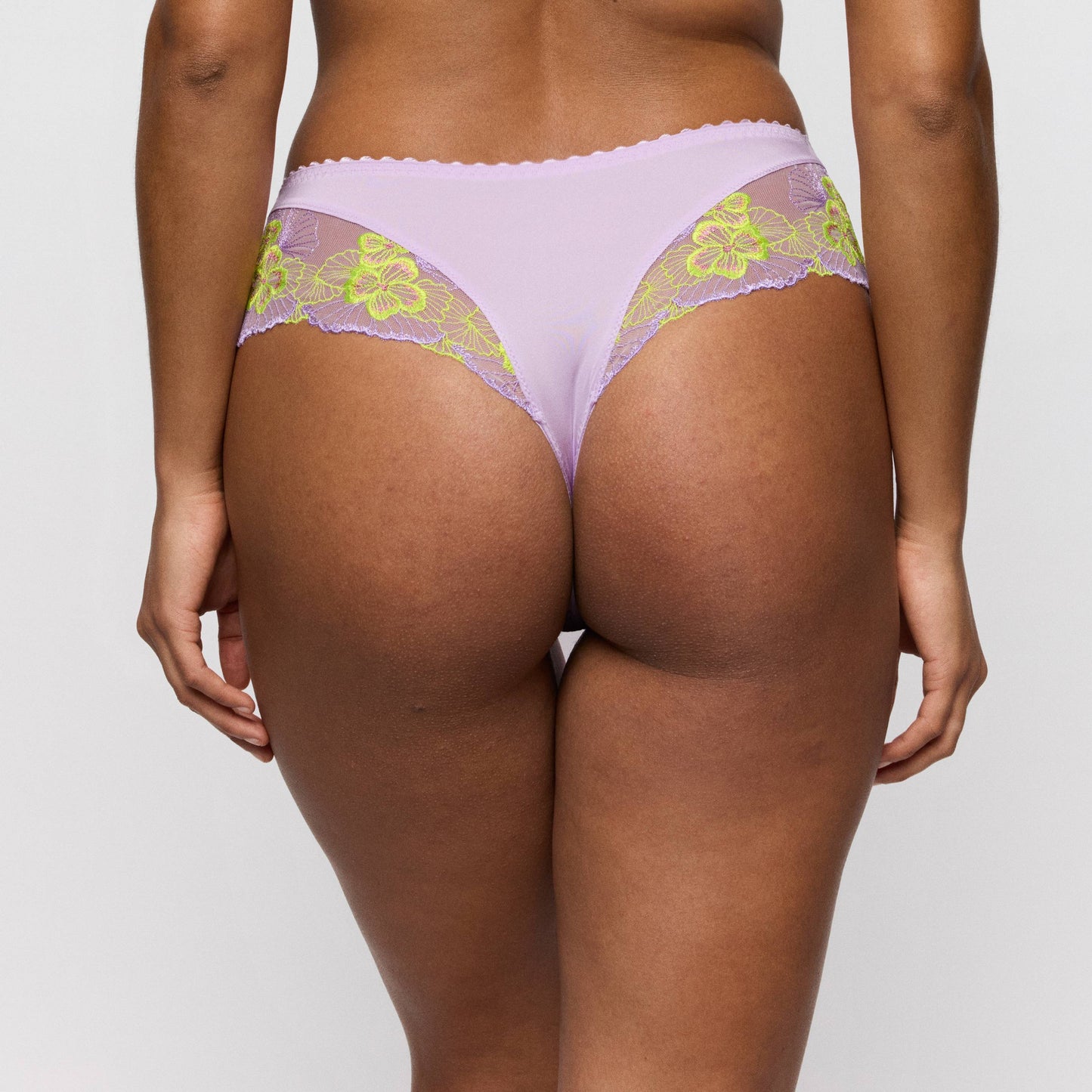 Primadonna IXIA luxury thong in Wisteria displayed from the back, featuring lilac fabric and lime floral lace detailing.